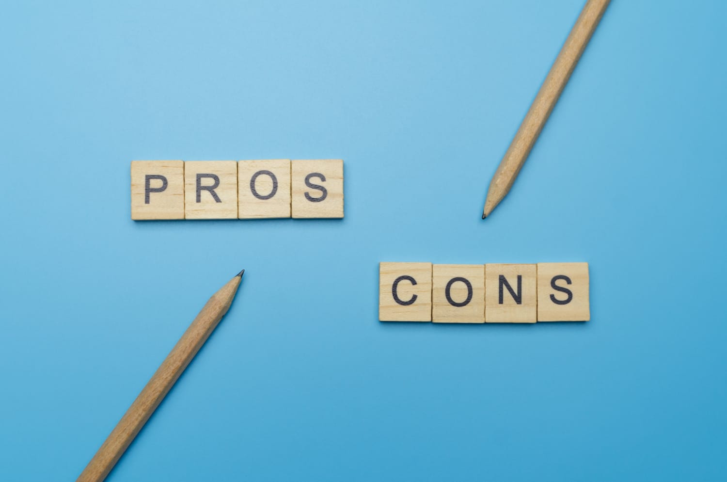 Wooden Cubes On A Blue Background That Say Pros And Cons