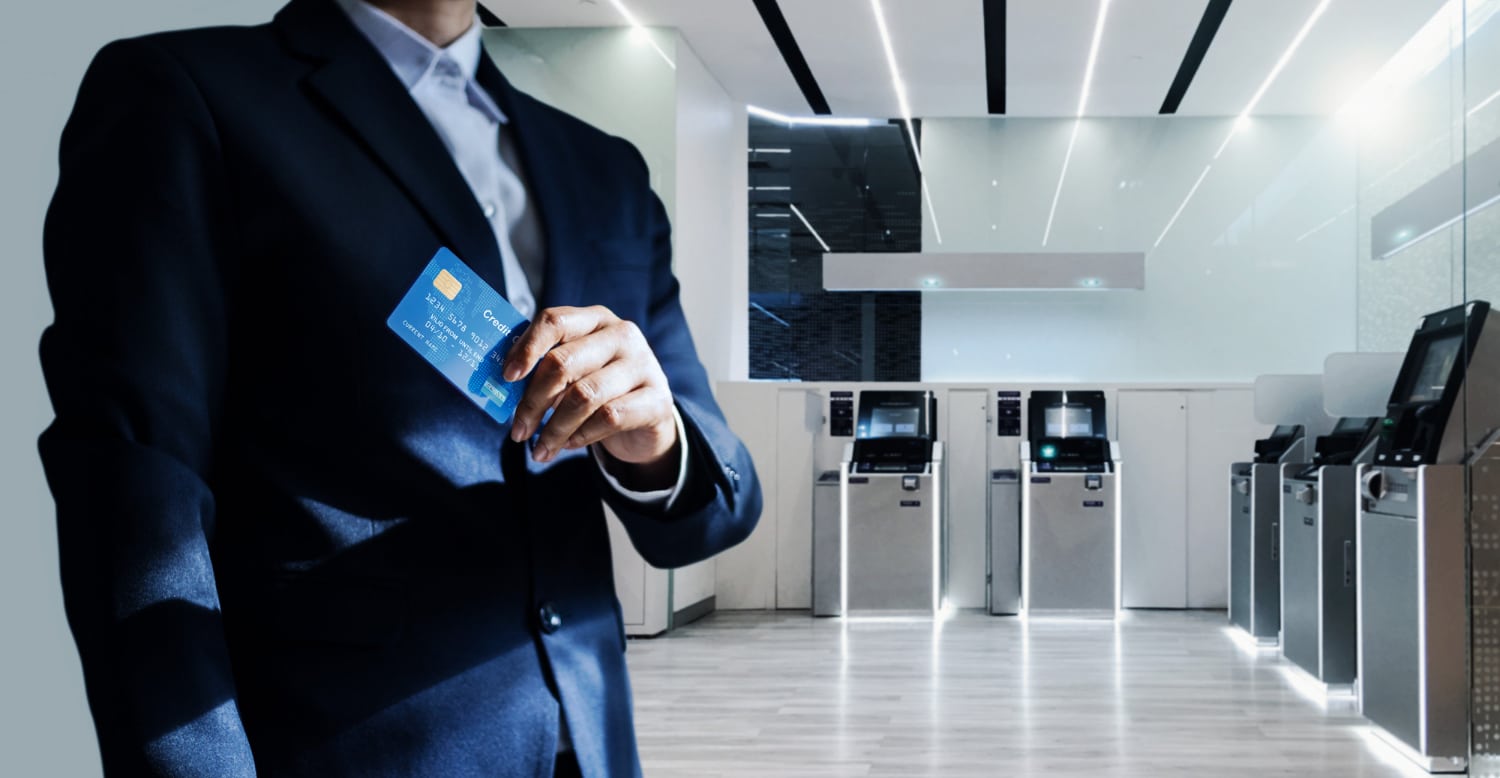Businessman Holding Credit Card With ATM Machines Background