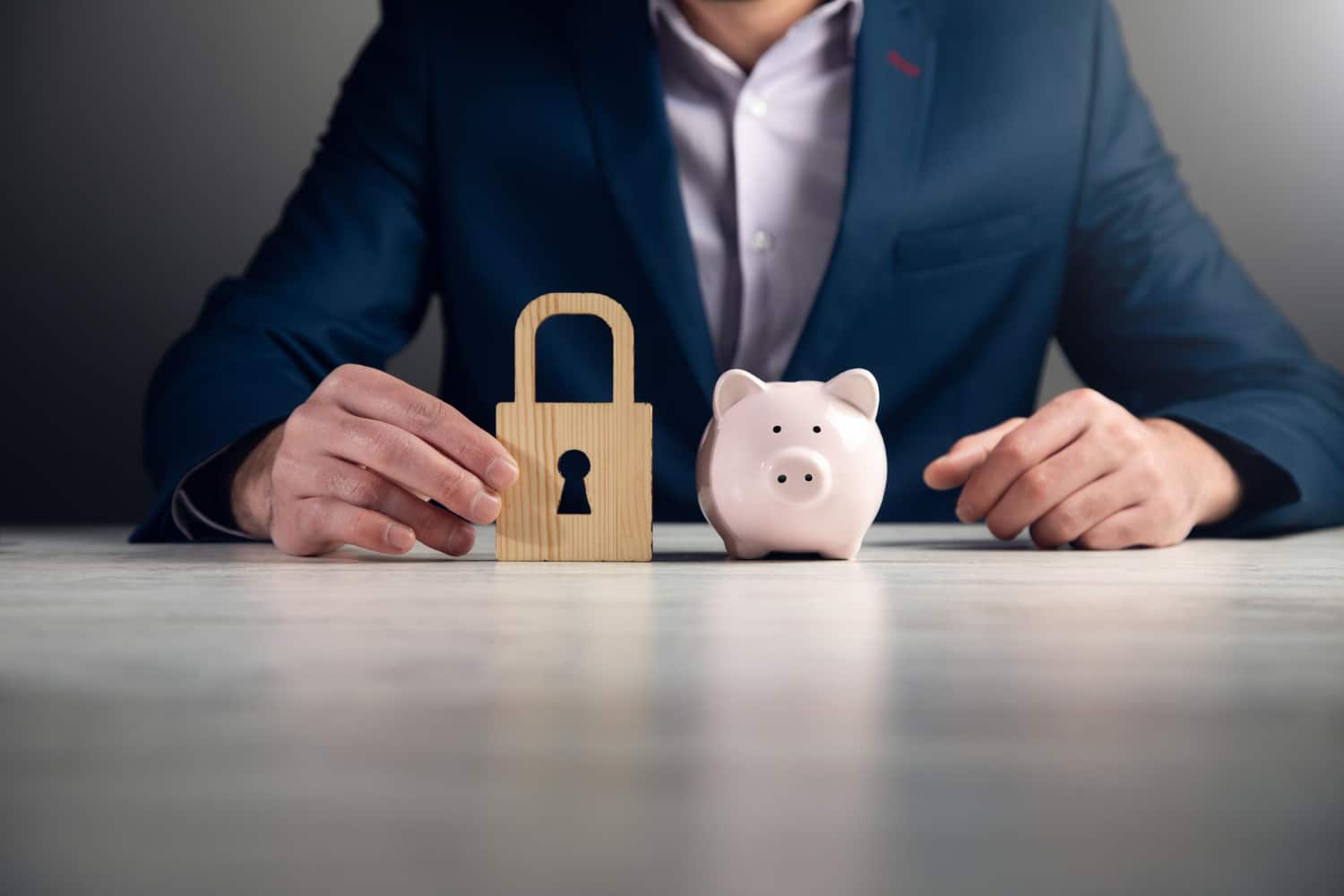 Businessman With Secure Lock And Piggy Bank On Desk
