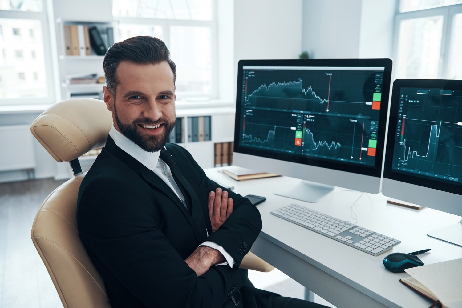 Confident Businessman Smiling In Office With Financial Graphs On Monitors