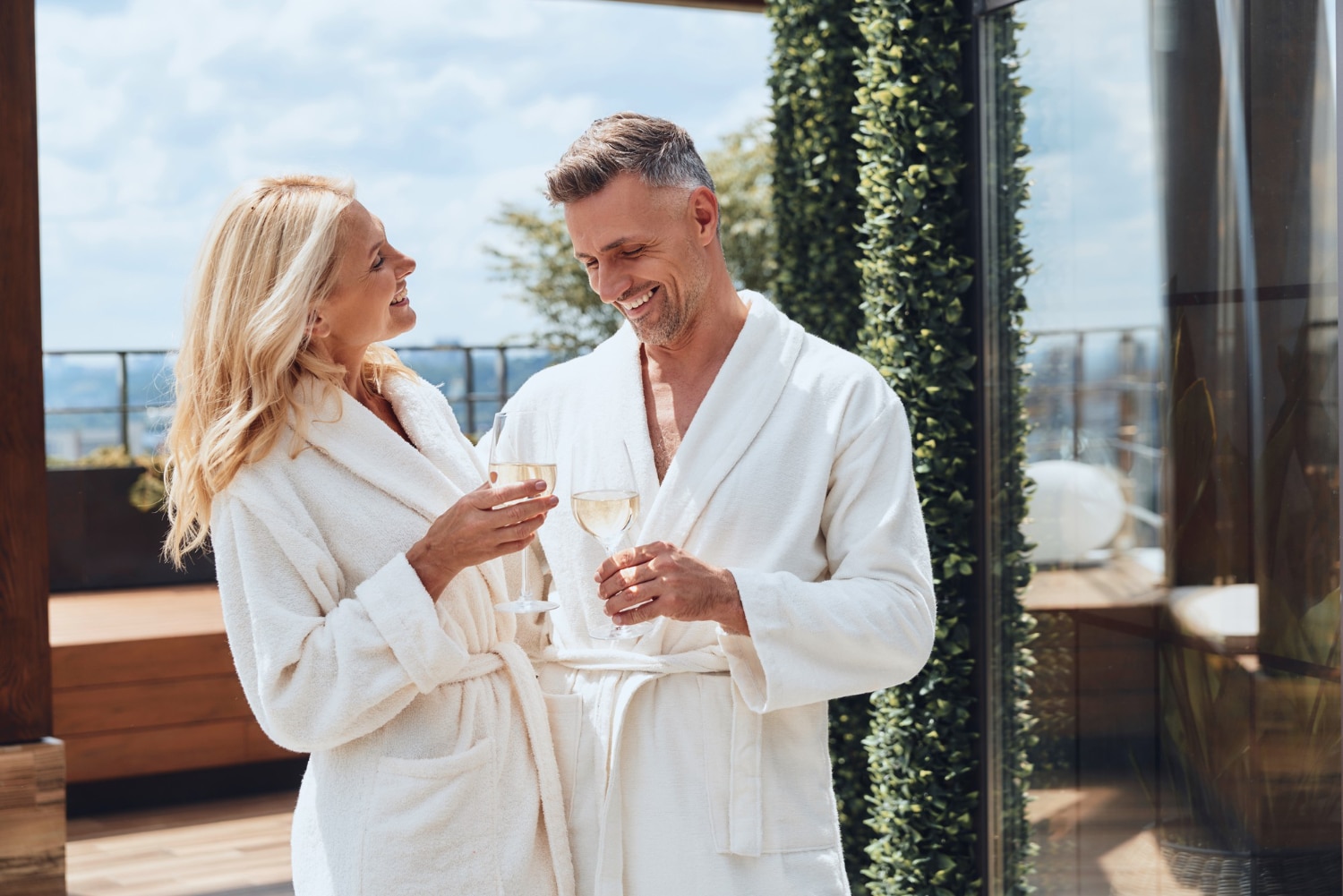 Couple Enjoying Champagne On Sunny Balcony In Robes