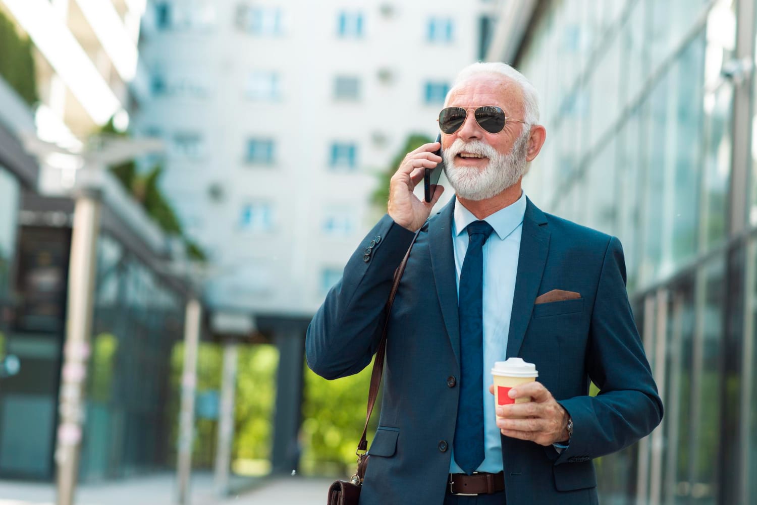 Elegant Senior Businessman Talking On Phone With Coffee Outdoors
