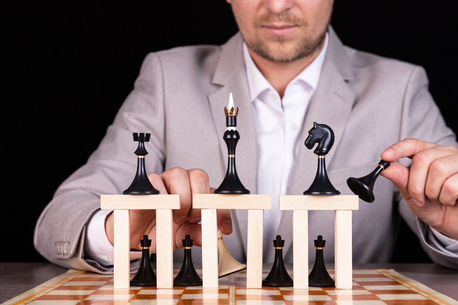 Man Balancing Chess Pieces On Wooden Blocks